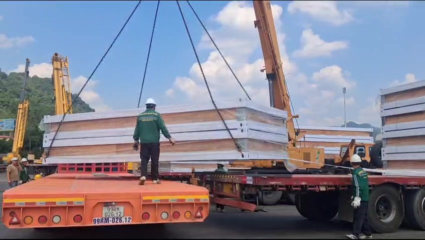 友谊关转车过驳过程中,现场人员配合越南海防项目打包箱构件在承运车辆上落位